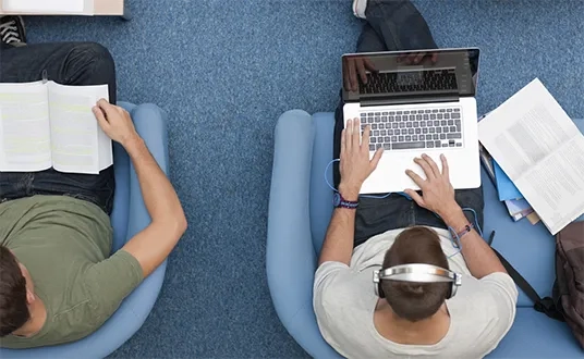 Junge Menschen mit Laptop, Kopfhörer und Büchern — die dynamische Medien- und Unterhaltungsbranche profitiert von maßgeschneidertem Consulting